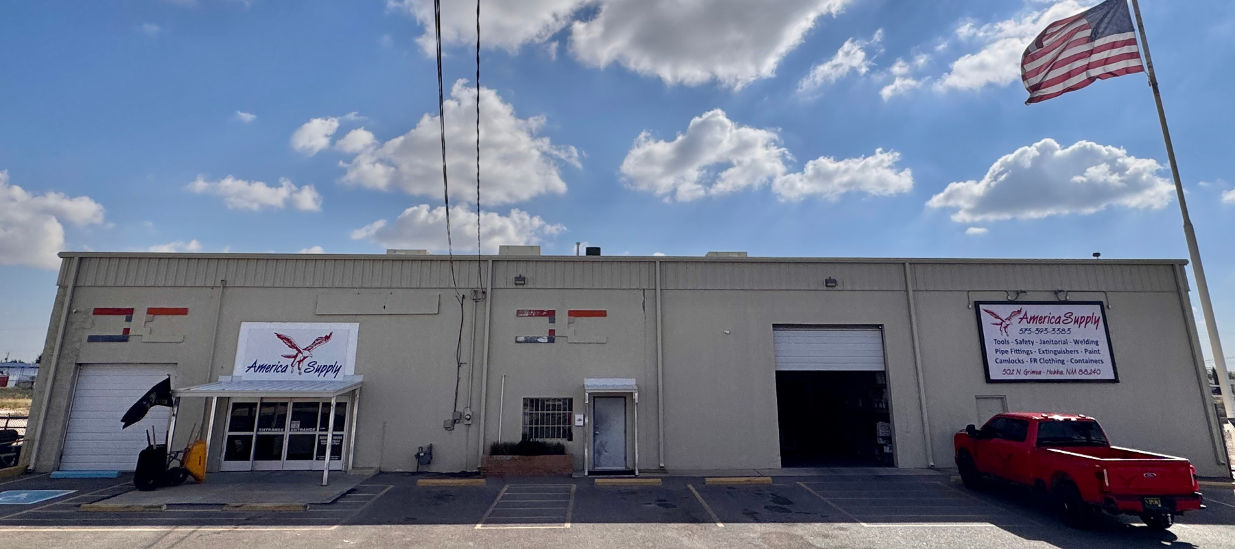 The store front of America Supply LLC on a clear day,, with the American flag full staff.